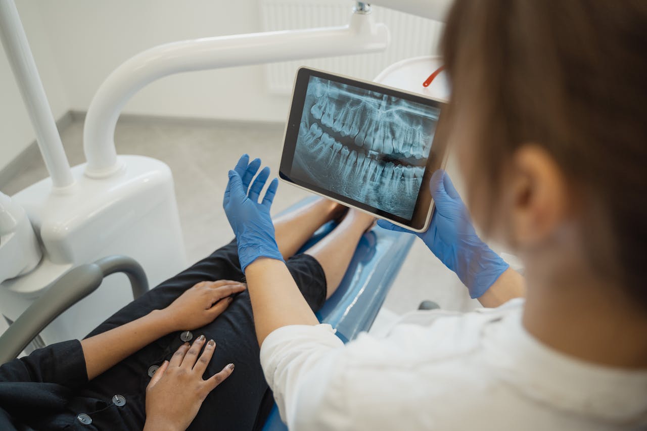 A dentist showing a dental x-ray on a tablet to a patient in a clinic.